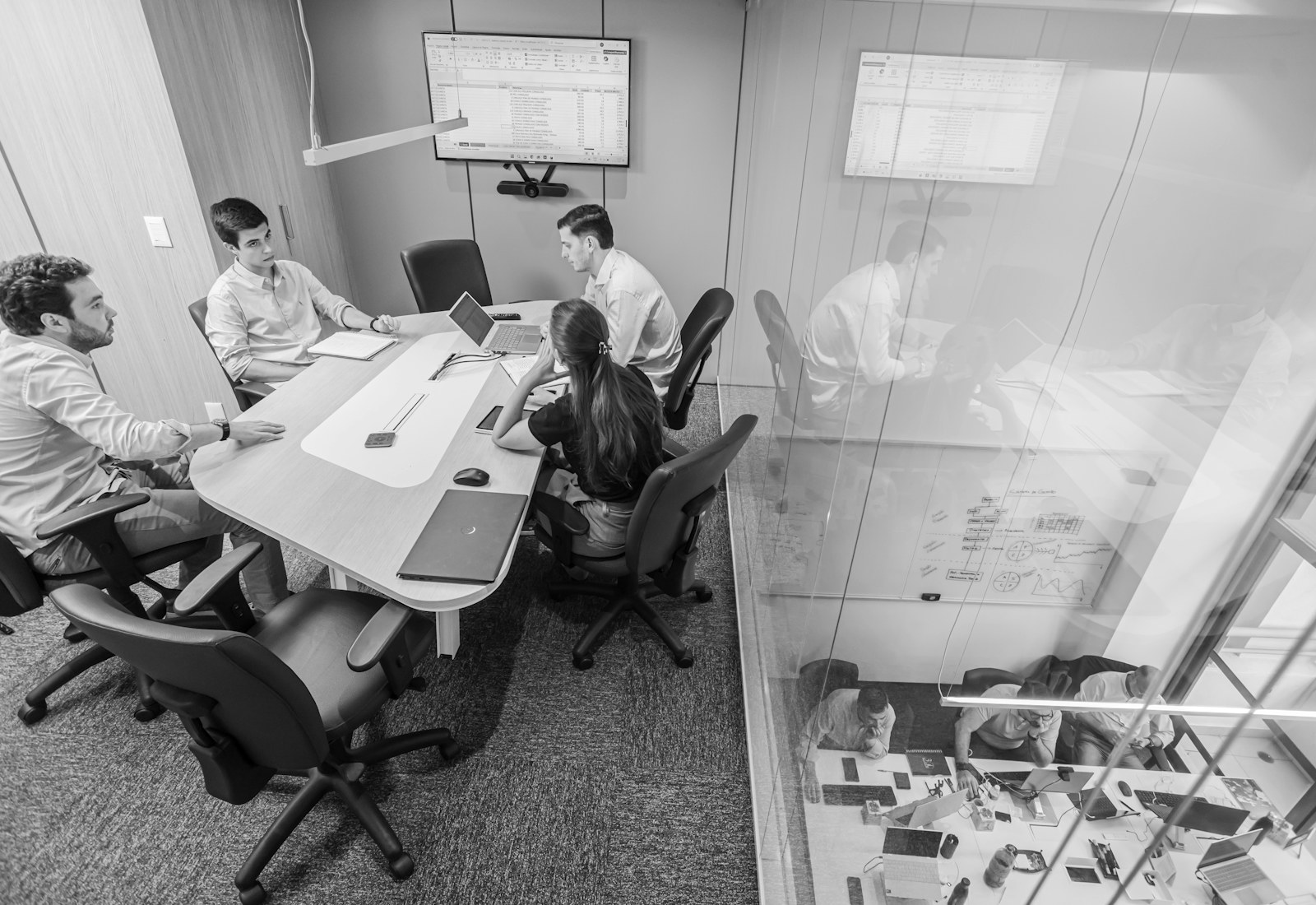 Corporate team in a glass-walled strategy meeting.