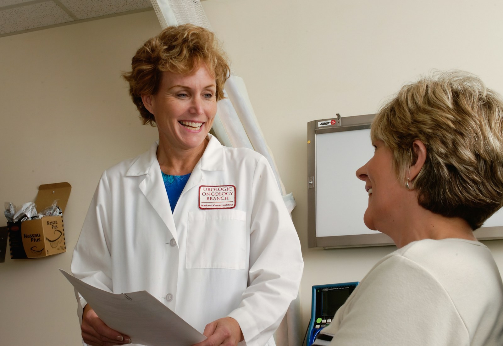 A physician speaking with a patient in a clinical setting.