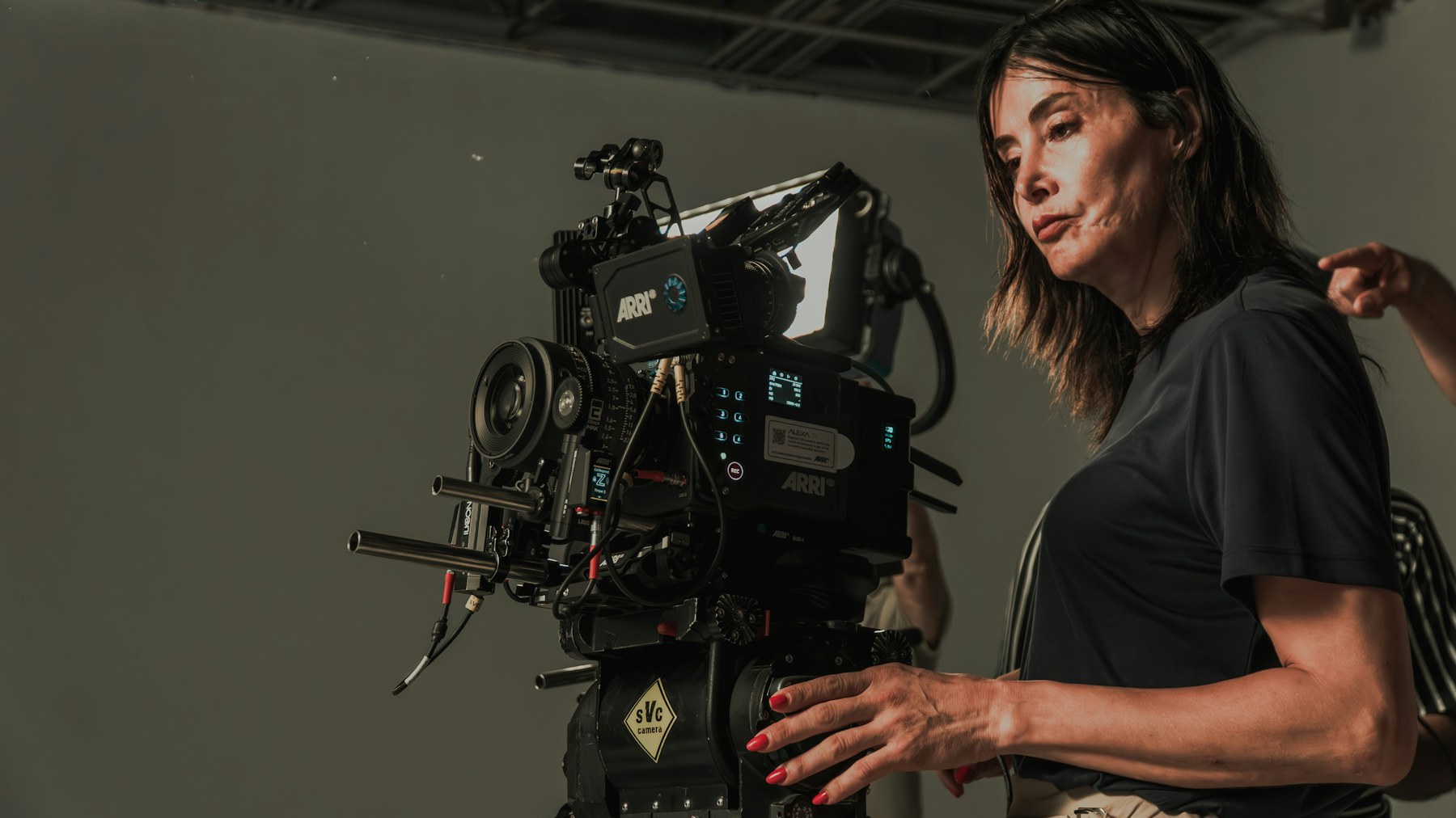 A professional camera operator preparing a cinema camera in a studio.